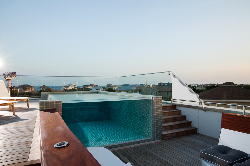 Réalisation d'une petite piscine sur toit à débordement minimaliste rectangle avec une terrasse en bois.