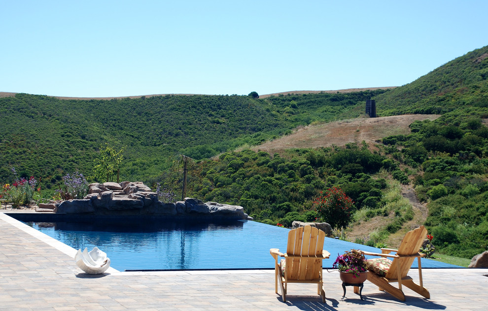 Imagen de piscina con fuente infinita moderna grande rectangular en patio trasero con suelo de hormigón estampado