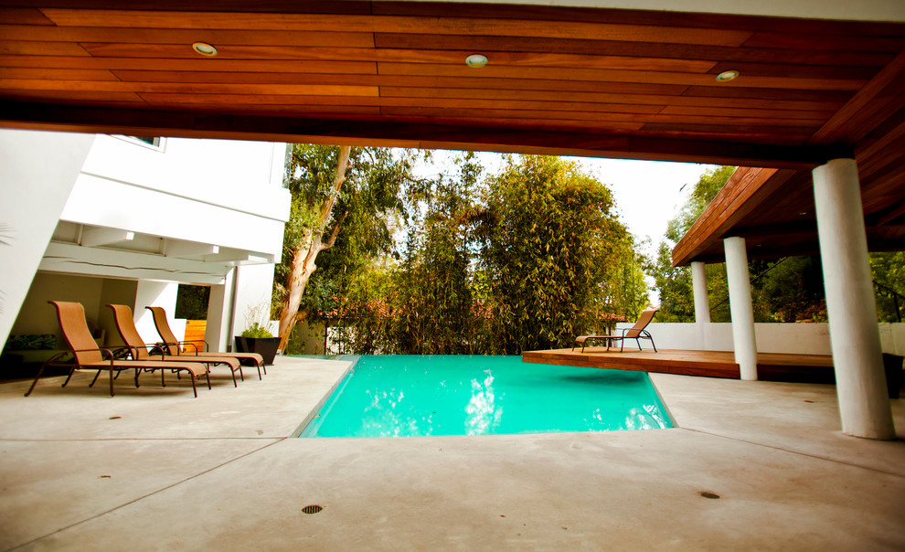Foto di una grande piscina moderna rettangolare dietro casa con lastre di cemento