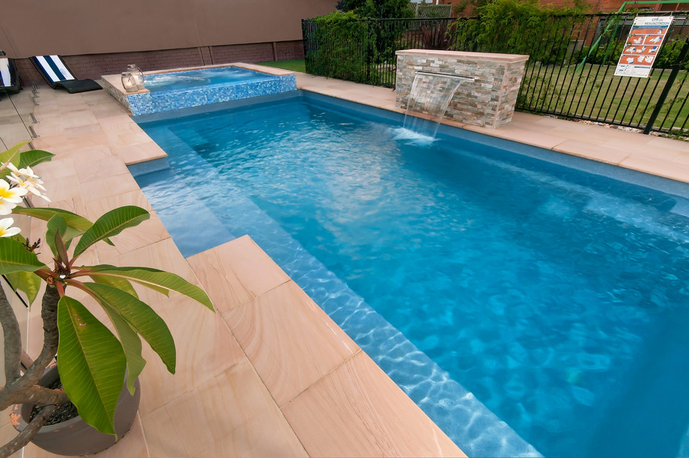 Immagine di una piscina a sfioro infinito stile marino rettangolare di medie dimensioni e dietro casa con una vasca idromassaggio e piastrelle