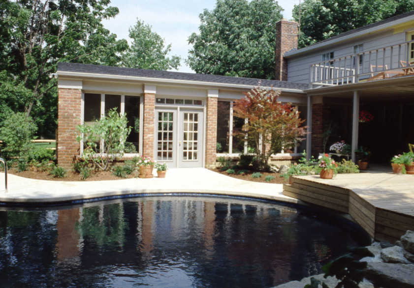 Diseño de piscina natural moderna de tamaño medio a medida en patio trasero con adoquines de piedra natural