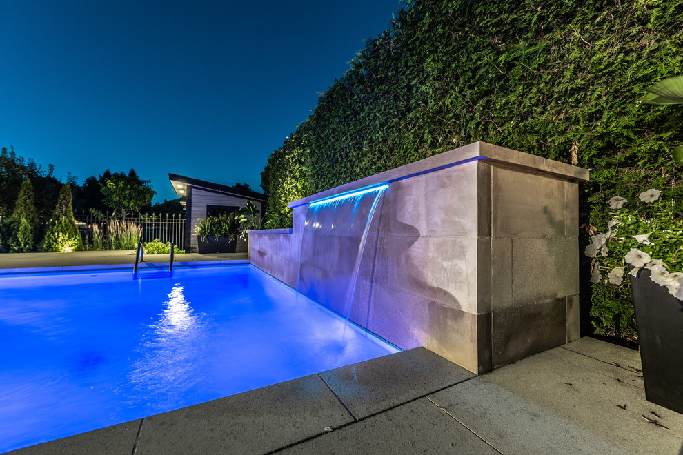 This is an example of a medium sized traditional back rectangular lengths swimming pool in Toronto with a water feature and brick paving.