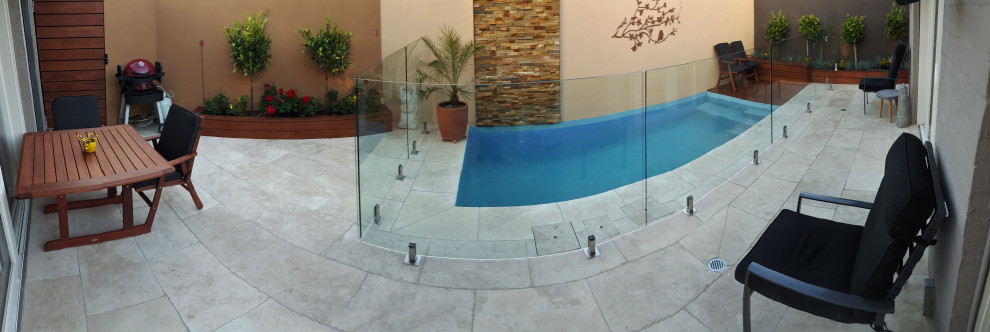 Foto de piscina con fuente alargada actual de tamaño medio rectangular en patio trasero con adoquines de piedra natural