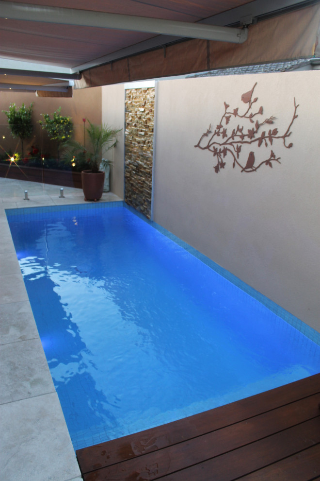 Пример оригинального дизайна: спортивный, прямоугольный бассейн среднего размера на заднем дворе в современном стиле с фонтаном и покрытием из каменной брусчатки