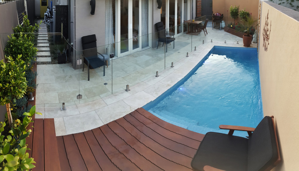 Diseño de piscina con fuente alargada actual de tamaño medio rectangular en patio trasero con adoquines de piedra natural