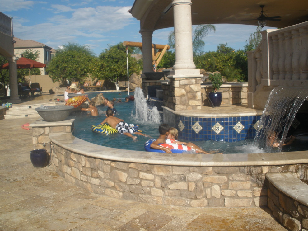 На фото: большой бассейн произвольной формы на заднем дворе в средиземноморском стиле с водной горкой и покрытием из плитки