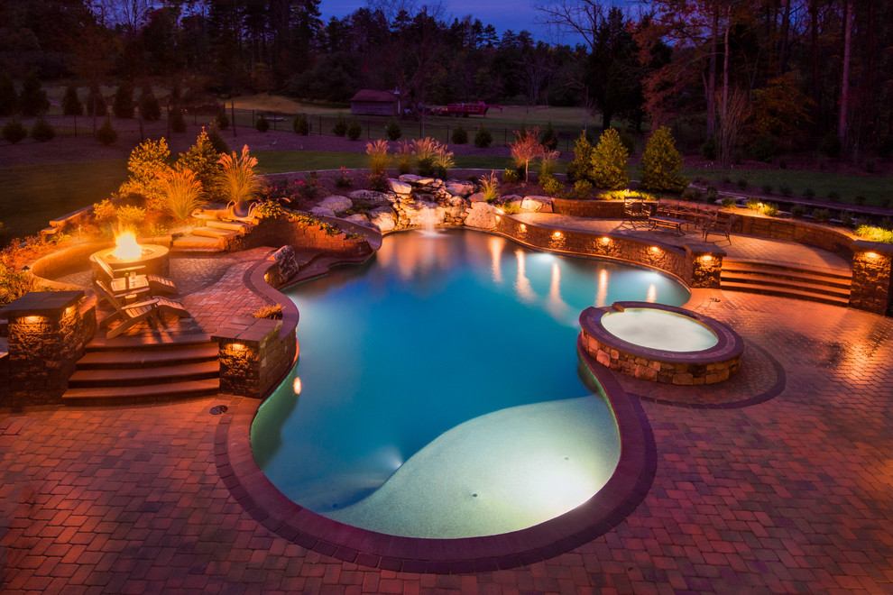 На фото: бассейн среднего размера, произвольной формы на заднем дворе в стиле неоклассика (современная классика) с мощением клинкерной брусчаткой