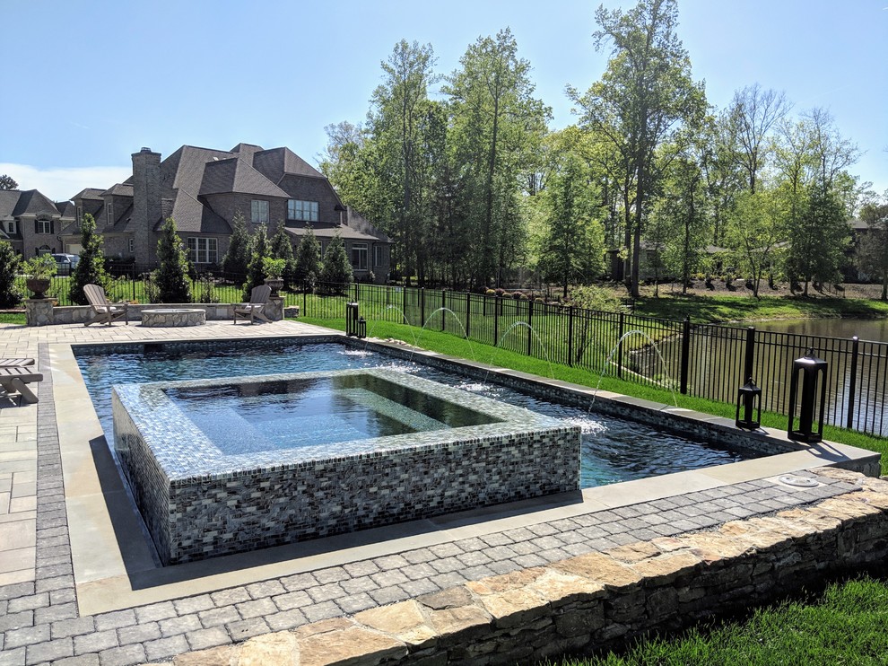 Esempio di una piscina a sfioro infinito contemporanea rettangolare di medie dimensioni e dietro casa con una vasca idromassaggio e pavimentazioni in cemento