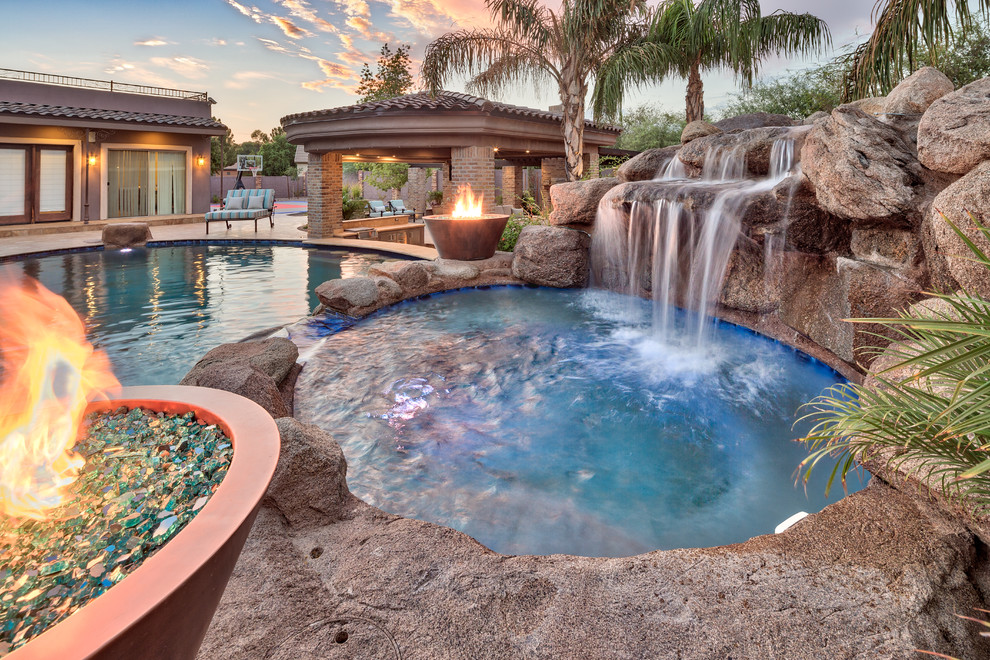Modelo de piscina natural mediterránea grande en patio trasero con adoquines de piedra natural