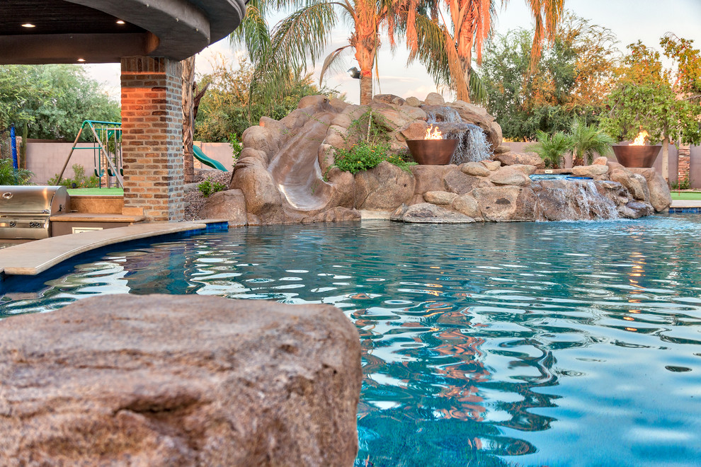 Ejemplo de piscina natural mediterránea grande en patio trasero con adoquines de piedra natural
