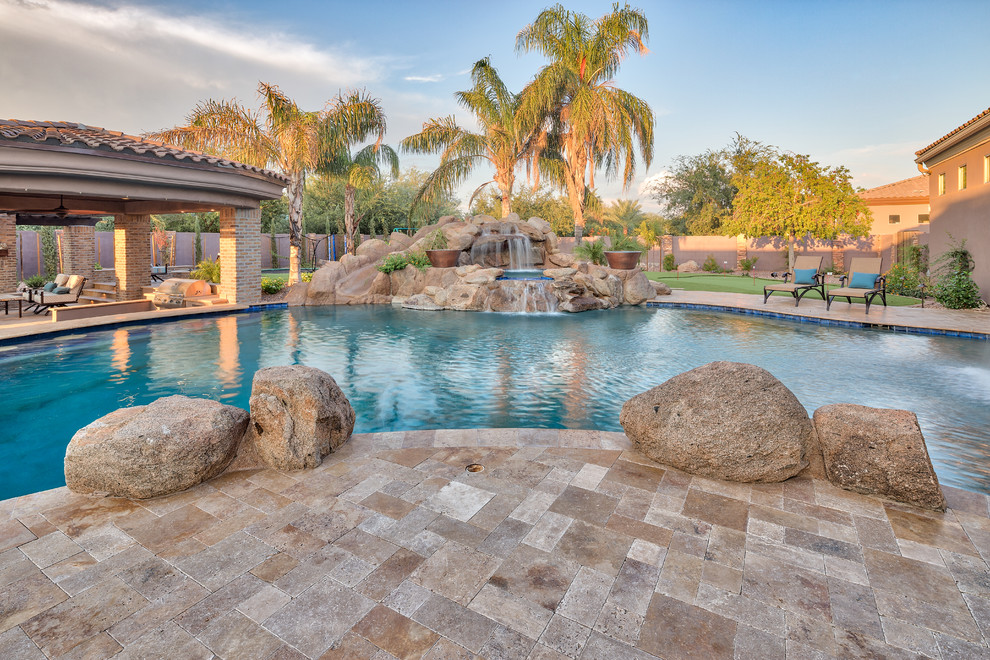 Стильный дизайн: большой естественный бассейн на заднем дворе в средиземноморском стиле с покрытием из каменной брусчатки - последний тренд