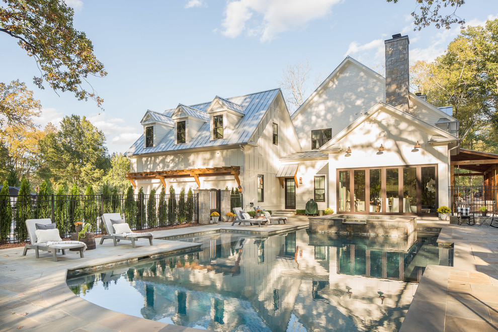 Esempio di una grande piscina naturale country personalizzata dietro casa con una vasca idromassaggio e pavimentazioni in pietra naturale