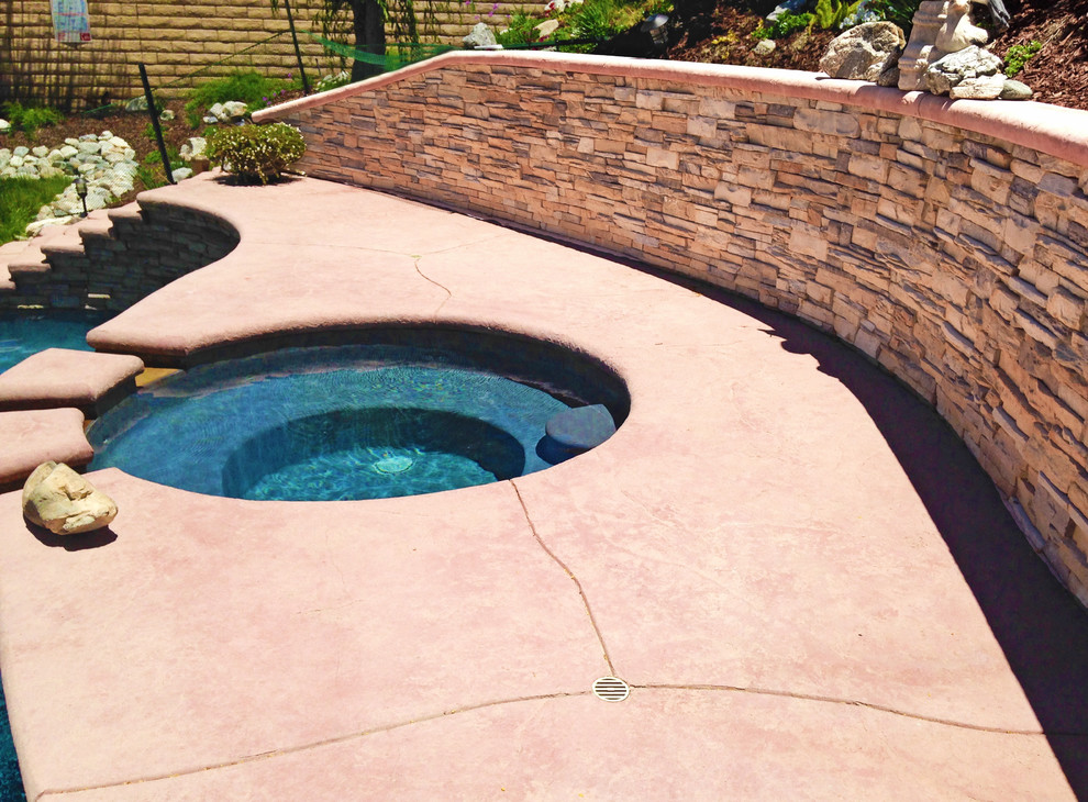 Diseño de piscina elevada mediterránea de tamaño medio a medida en patio trasero con suelo de hormigón estampado