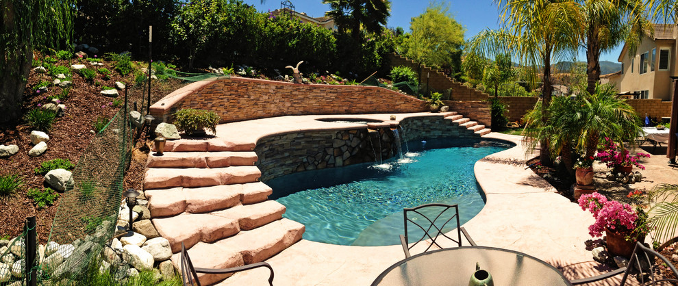 Imagen de piscina elevada mediterránea de tamaño medio a medida en patio trasero con suelo de hormigón estampado