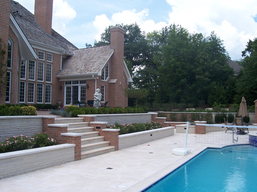 Idee per una grande piscina naturale tradizionale personalizzata dietro casa con pavimentazioni in pietra naturale e una vasca idromassaggio
