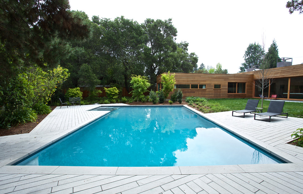 Ejemplo de piscinas y jacuzzis alargados contemporáneos grandes en forma de L en patio trasero con adoquines de hormigón