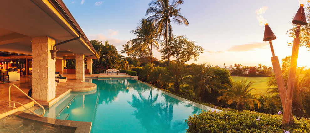 Ejemplo de piscinas y jacuzzis infinitos tropicales extra grandes a medida en patio trasero con adoquines de hormigón