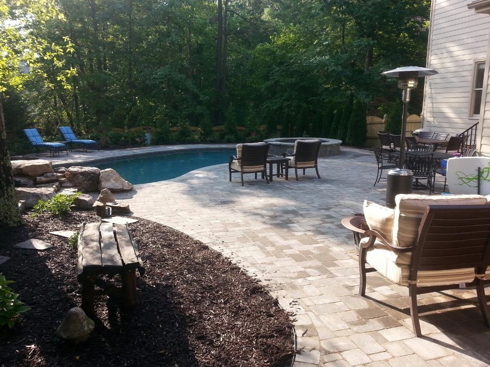 Ejemplo de piscinas y jacuzzis naturales clásicos de tamaño medio tipo riñón en patio trasero con adoquines de hormigón