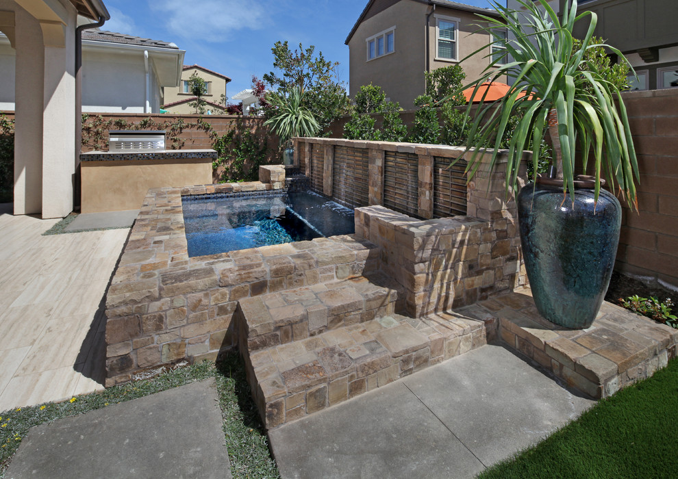Пример оригинального дизайна: большой прямоугольный бассейн на заднем дворе в стиле модернизм с джакузи и покрытием из каменной брусчатки