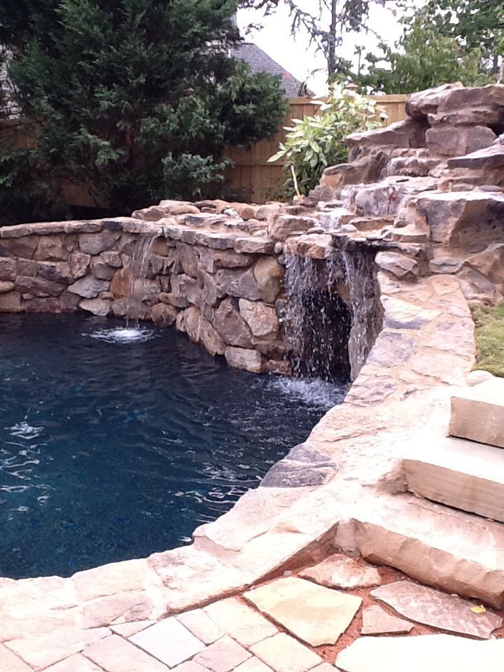 Diseño de piscina con fuente natural tradicional renovada pequeña a medida en patio trasero con adoquines de piedra natural
