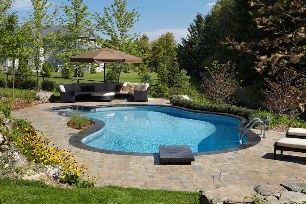 Foto di una grande piscina naturale classica personalizzata dietro casa con fontane e pavimentazioni in mattoni