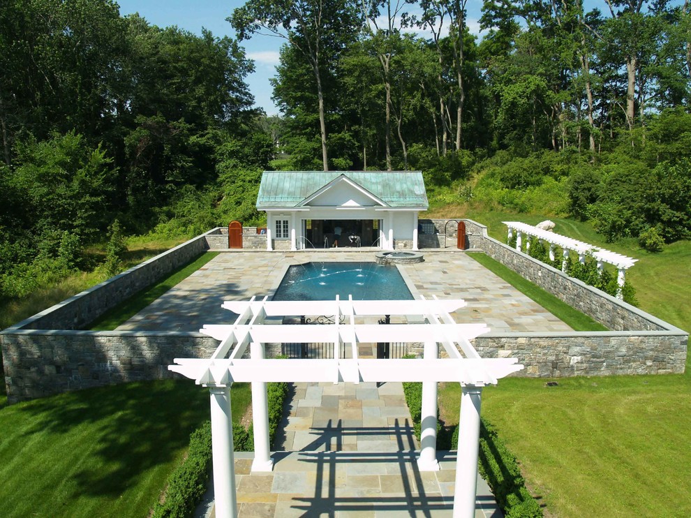 Large traditional side rectangular natural swimming pool in New York with a pool house and natural stone paving.