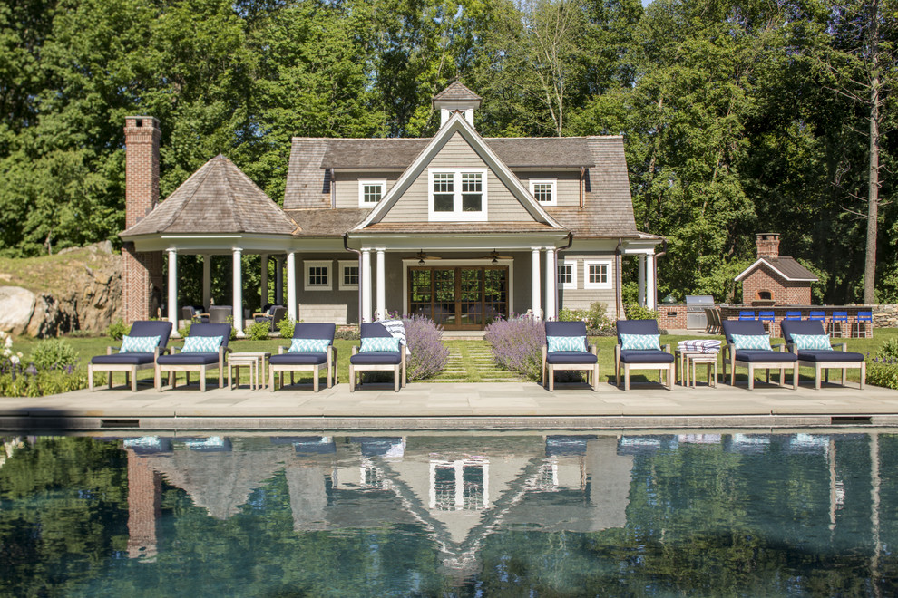 Large victorian back rectangular lengths swimming pool in New York with a pool house and stamped concrete.