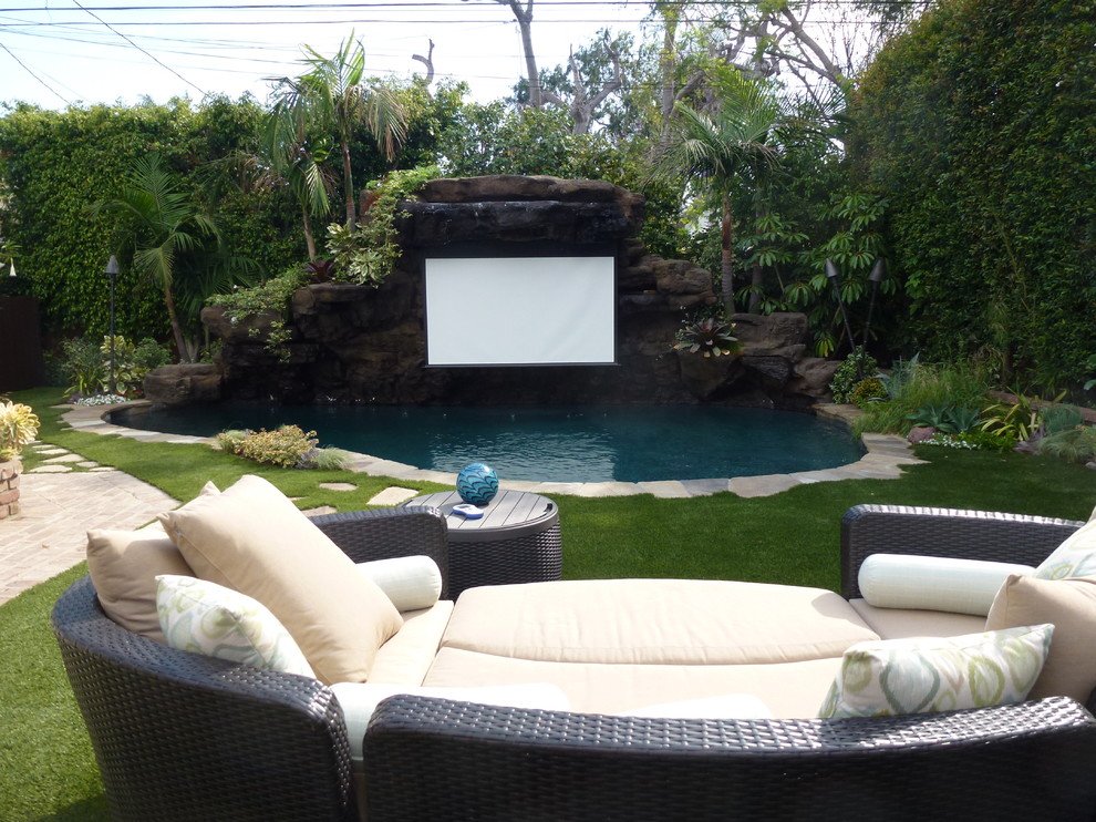 Foto de piscina natural tropical pequeña a medida en patio trasero con losas de hormigón