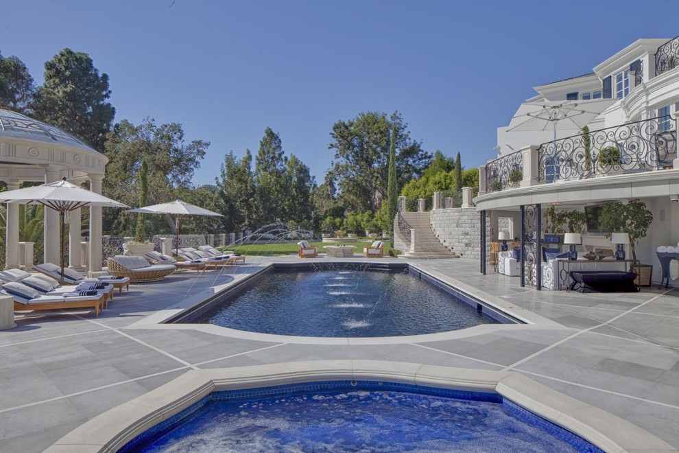 Idee per una grande piscina monocorsia tradizionale rettangolare dietro casa con piastrelle e fontane