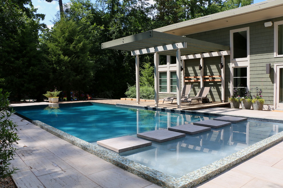 Imagen de piscina con fuente infinita minimalista de tamaño medio rectangular en patio con adoquines de hormigón