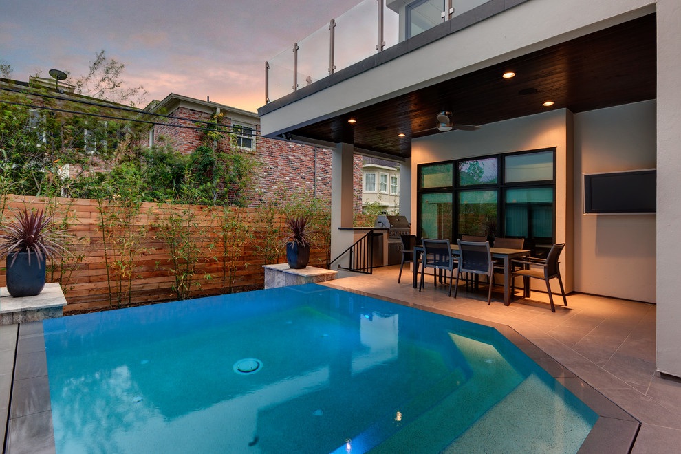 Photo of a large contemporary back custom shaped infinity swimming pool in Houston with a bbq area.
