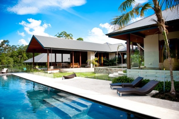 Idee per un'ampia piscina monocorsia tropicale rettangolare in cortile con una dépendance a bordo piscina e pavimentazioni in pietra naturale