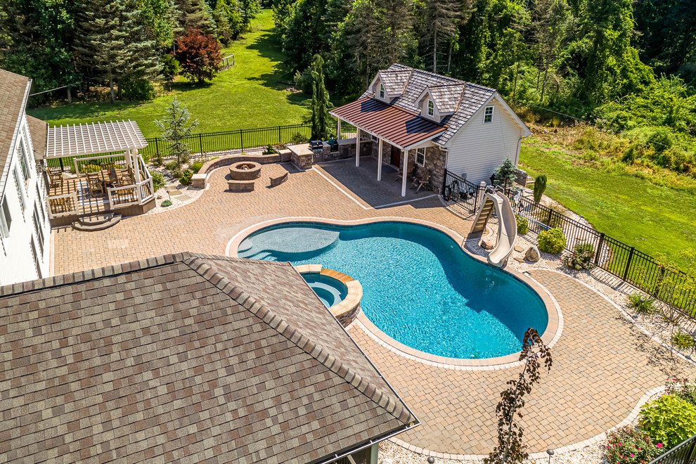 Foto de casa de la piscina y piscina tradicional grande a medida en patio trasero con adoquines de hormigón