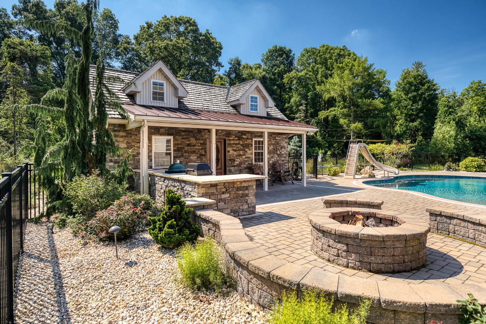Foto de casa de la piscina y piscina clásica grande a medida en patio trasero con adoquines de hormigón