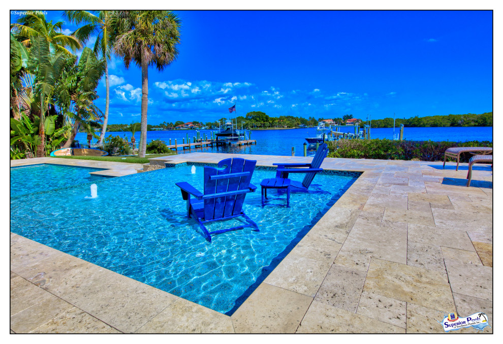 Inspiration for an expansive modern courtyard custom shaped lengths swimming pool in Tampa with a pool house and natural stone paving.