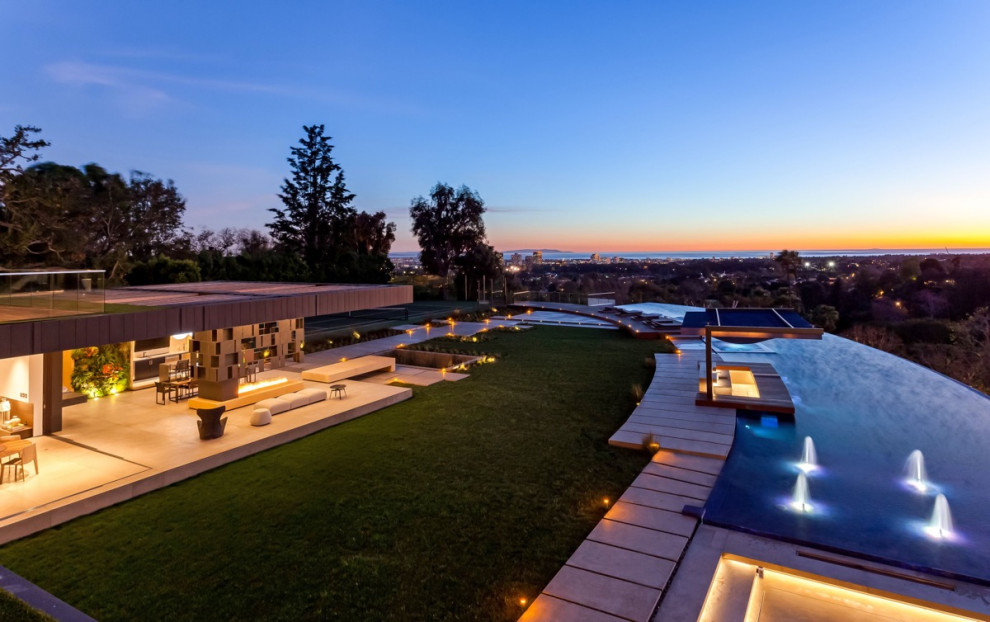 Inspiration for a huge contemporary backyard custom-shaped infinity pool fountain remodel in Los Angeles with decking