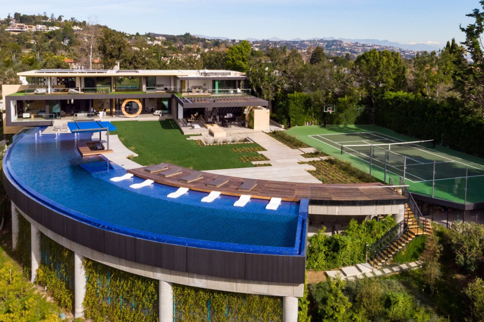 Immagine di un'ampia piscina a sfioro infinito contemporanea personalizzata dietro casa con fontane e pedane