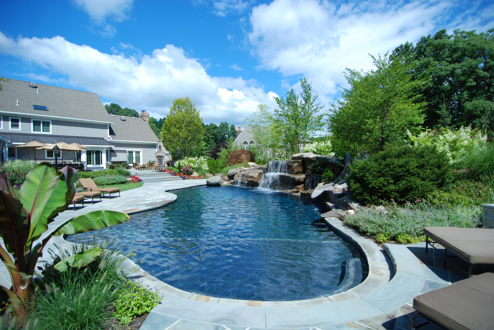 Foto de piscina con tobogán natural tradicional grande a medida en patio trasero con adoquines de piedra natural