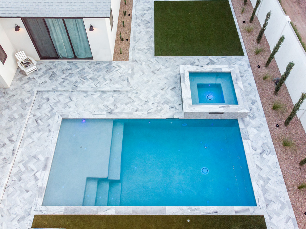 Aménagement d'une piscine arrière moderne de taille moyenne et rectangle avec un bain bouillonnant et des pavés en pierre naturelle.