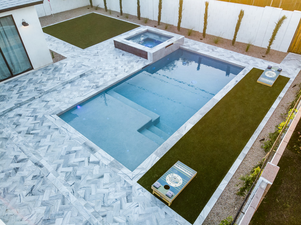Réalisation d'une piscine arrière minimaliste de taille moyenne et rectangle avec un bain bouillonnant et des pavés en pierre naturelle.