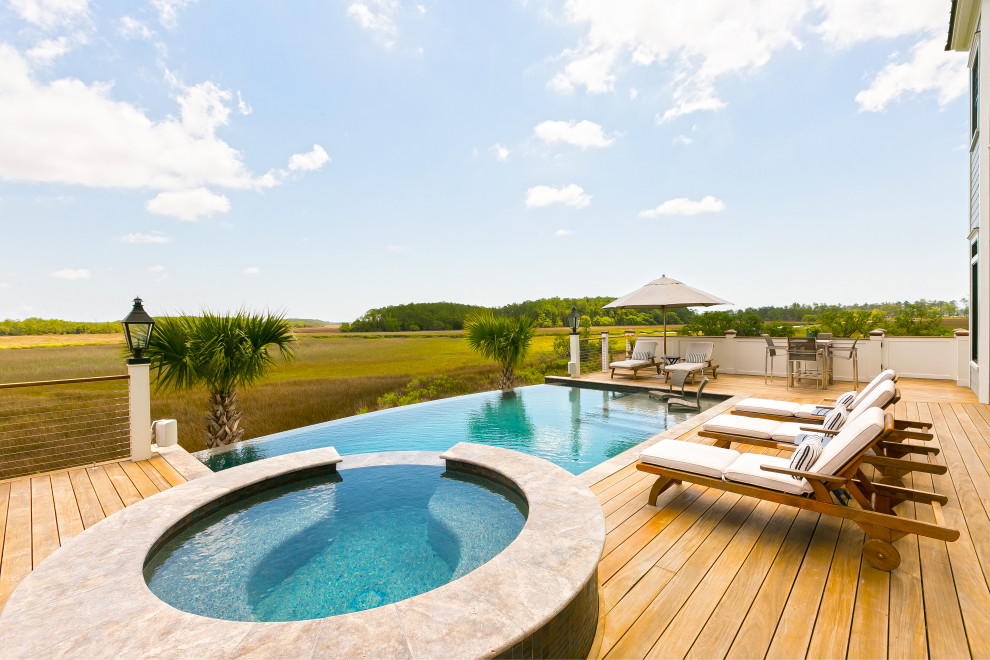 Idée de décoration pour une piscine à débordement marine rectangle avec un bain bouillonnant et une terrasse en bois.