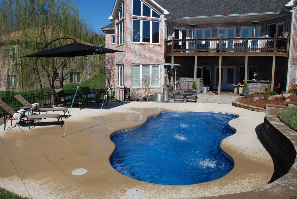 На фото: бассейн среднего размера, произвольной формы на заднем дворе в современном стиле с мощением тротуарной плиткой