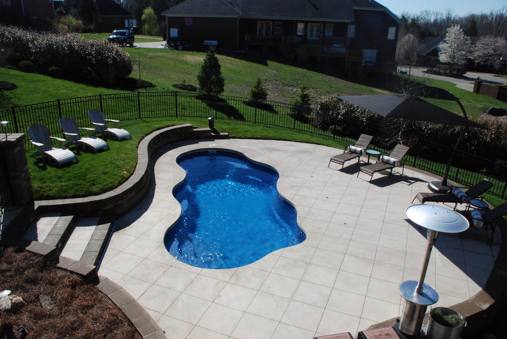 Imagen de piscina actual de tamaño medio a medida en patio trasero con adoquines de hormigón