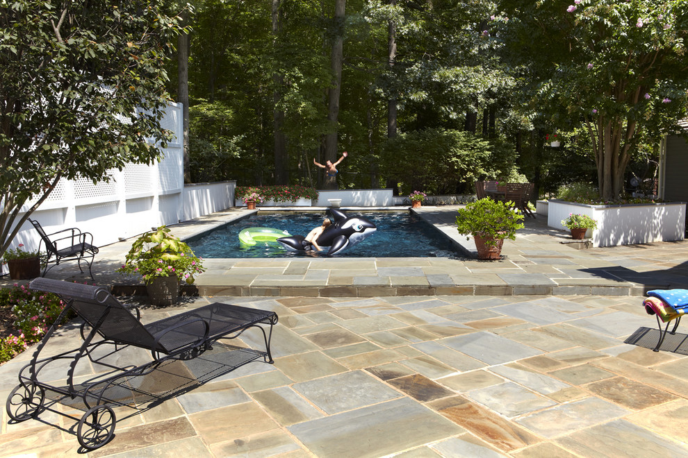 Foto de piscina alargada clásica de tamaño medio rectangular en patio trasero con adoquines de hormigón