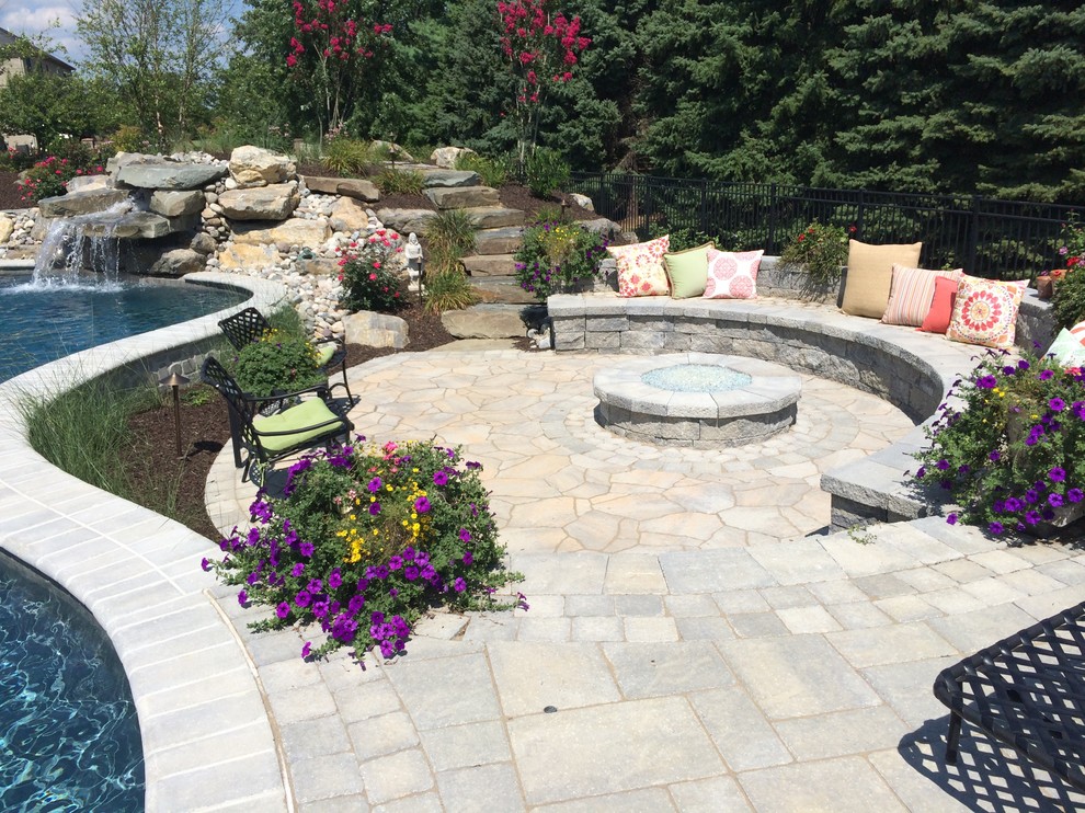 Large classic back custom shaped natural swimming pool in Philadelphia with concrete paving.