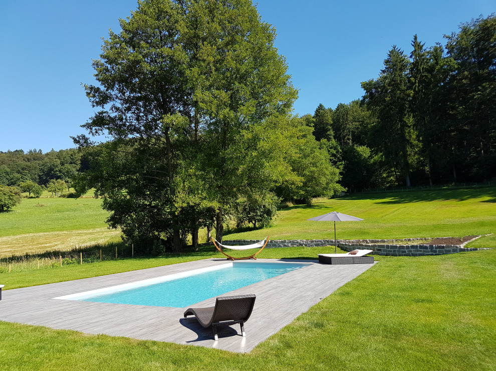 Imagen de piscina mediterránea grande rectangular en patio lateral con suelo de baldosas