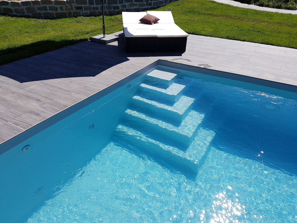 Modelo de piscina mediterránea grande rectangular en patio lateral con suelo de baldosas