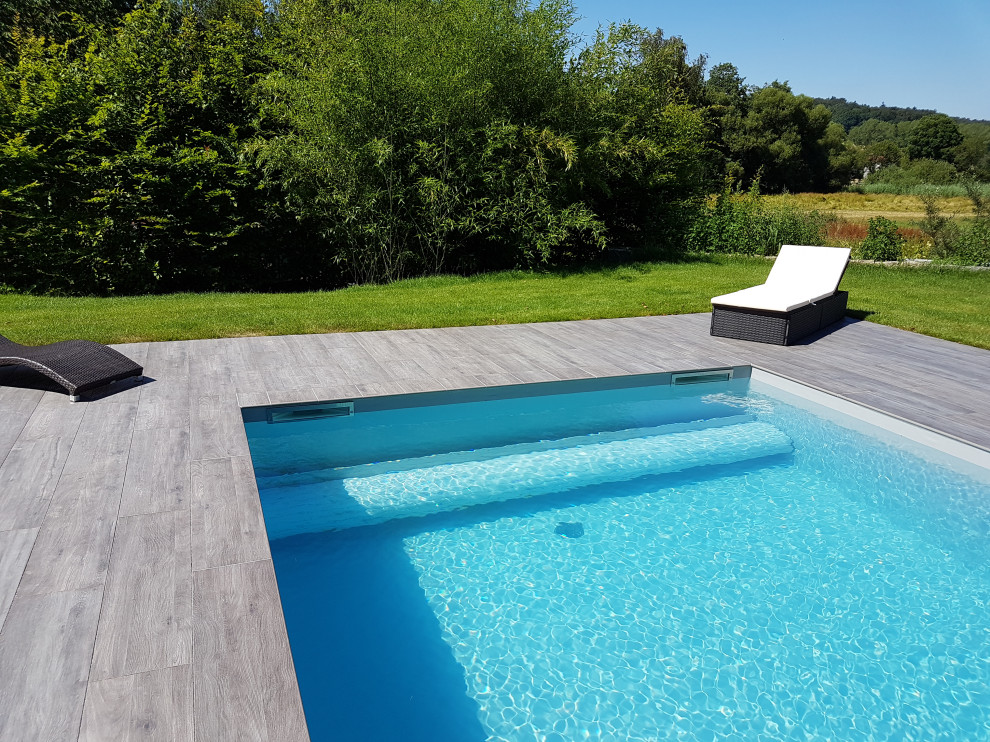 Modelo de piscina mediterránea grande rectangular en patio lateral con suelo de baldosas