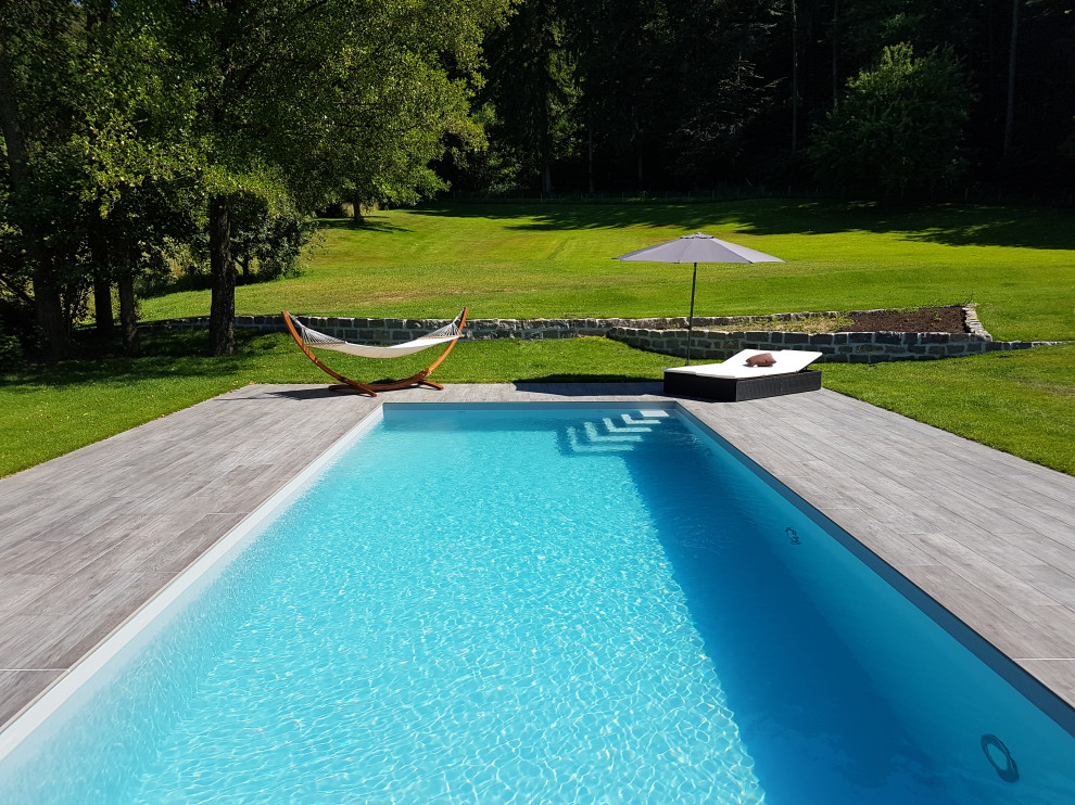 Aménagement d'une grande piscine latérale méditerranéenne rectangle avec du carrelage.