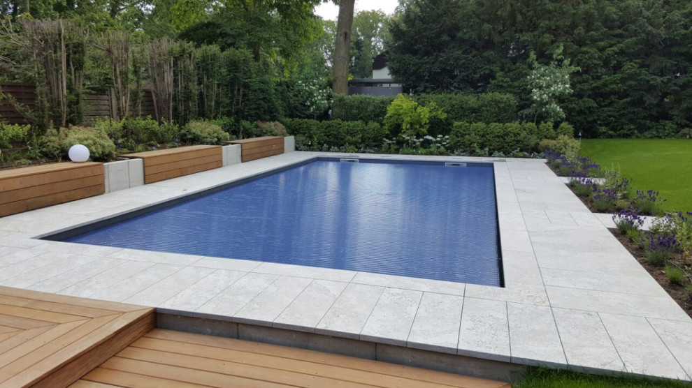 Imagen de piscina mediterránea grande rectangular en patio lateral con adoquines de piedra natural